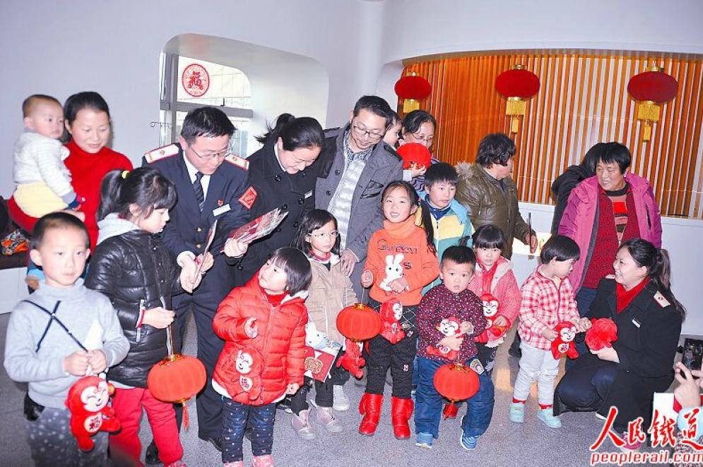 　　1月23日，上海站全国铁路劳动模范汤杰 （左五）带领服务团队在4号 “心尚”爱心候车室内为小旅客送上猴年吉祥物、新年贺卡和红灯笼，向候车的旅客提前拜年。 张锦渭 摄
